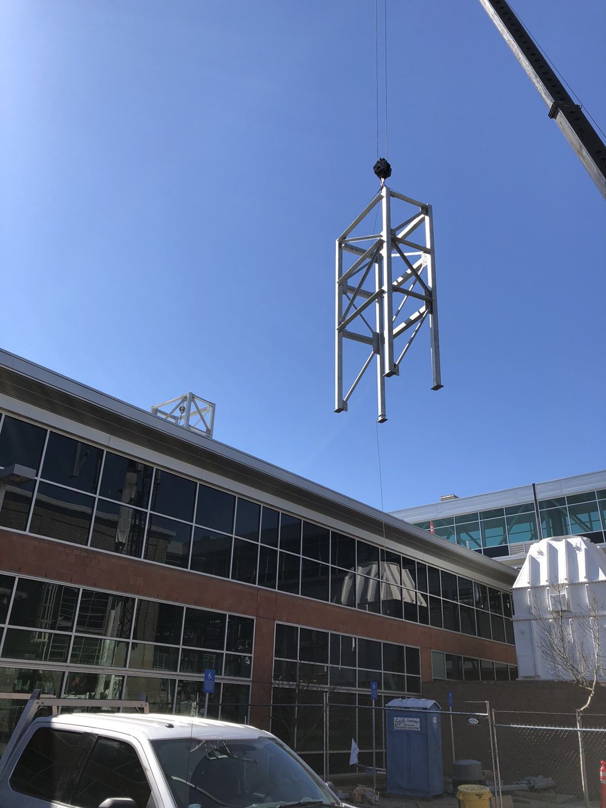 Steel frame section flying on the crane hook against a blue sky
